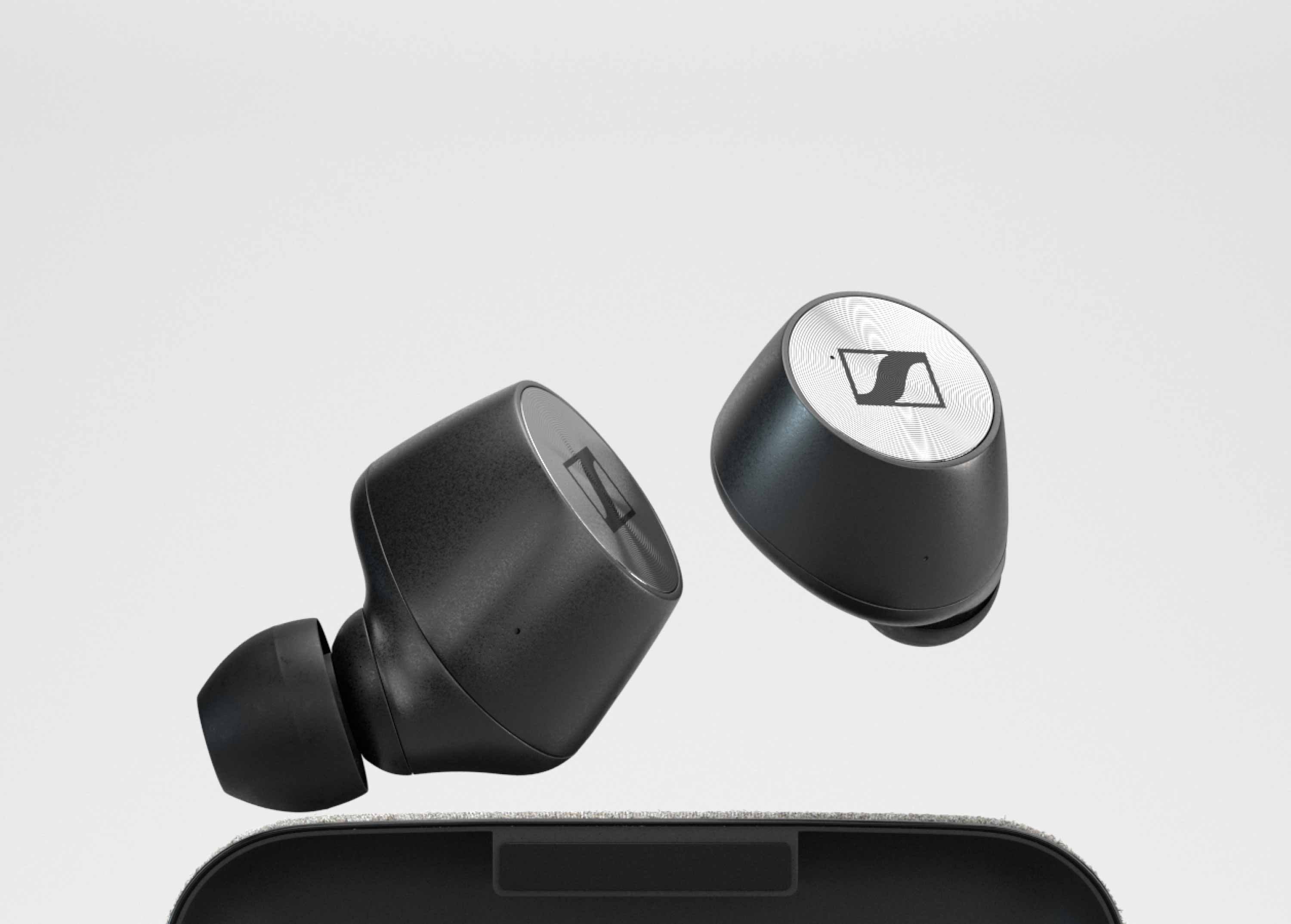 Two Sennheiser ear buds floating above their case